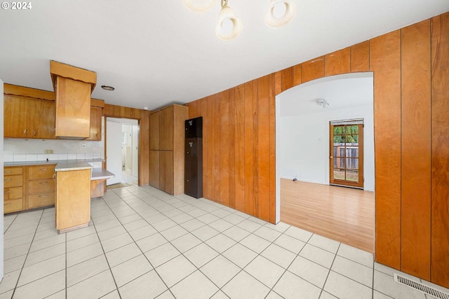 kitchen with wood walls, light tile patterned flooring, and tasteful backsplash