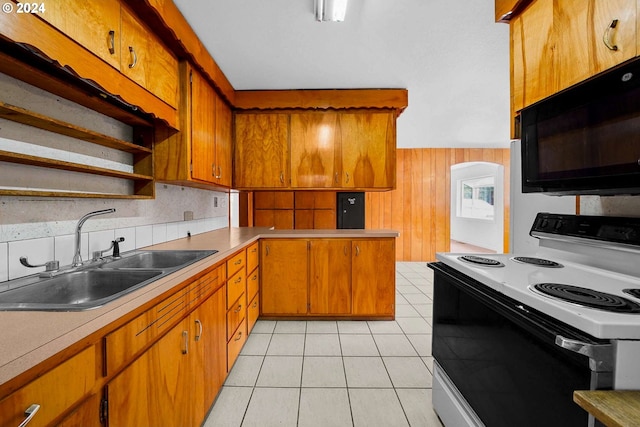 kitchen featuring wood walls, sink, white electric range oven, light tile patterned flooring, and kitchen peninsula