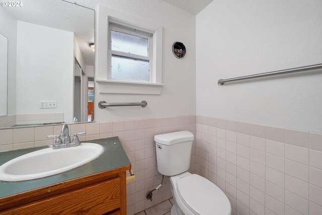 bathroom featuring vanity, toilet, and tile walls