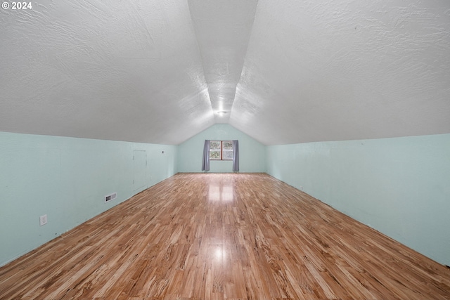 bonus room with hardwood / wood-style floors, a textured ceiling, and vaulted ceiling