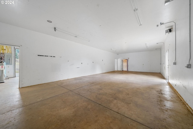 empty room with concrete flooring, electric panel, and water heater