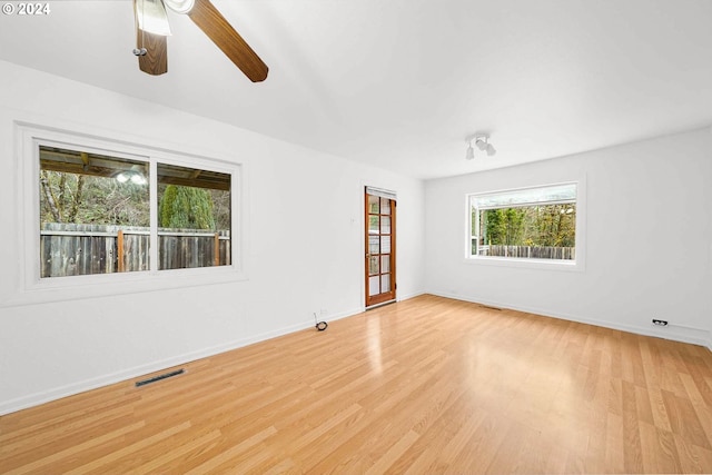 empty room with light hardwood / wood-style flooring, plenty of natural light, and ceiling fan