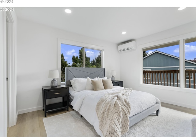 bedroom with an AC wall unit and light hardwood / wood-style floors