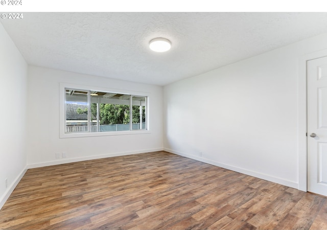 unfurnished room with a textured ceiling and dark wood-type flooring