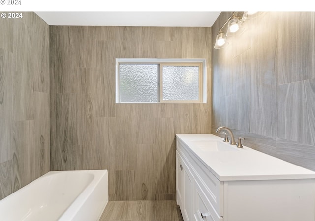 bathroom featuring a tub to relax in, vanity, and tile walls