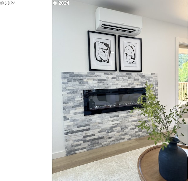 room details with hardwood / wood-style floors, a stone fireplace, and a wall mounted AC