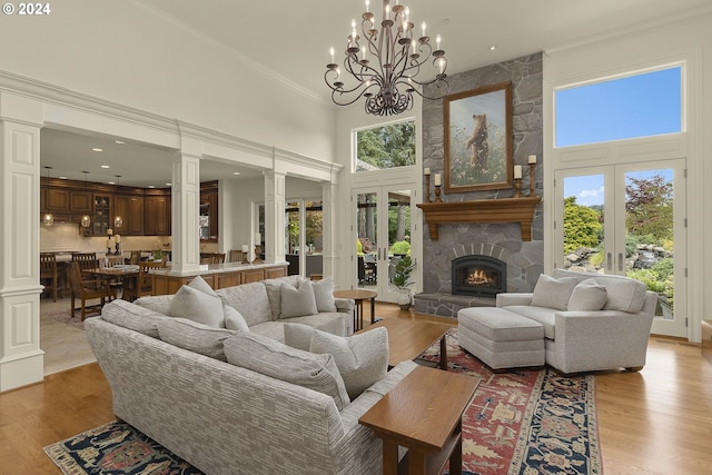 living room featuring a high ceiling, french doors, ornate columns, and plenty of natural light