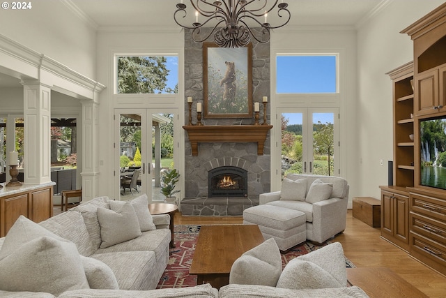 living room with a wealth of natural light, french doors, light wood-type flooring, and decorative columns