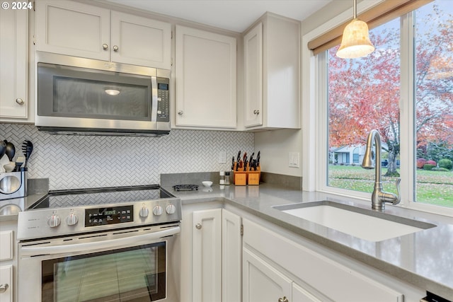 kitchen with white cabinets, sink, decorative backsplash, appliances with stainless steel finishes, and decorative light fixtures