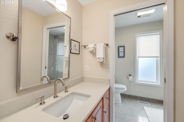 bathroom featuring tile patterned flooring, vanity, a shower with shower door, and toilet