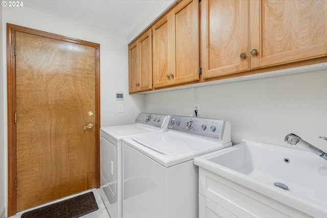 washroom with cabinets, light tile patterned floors, washer and clothes dryer, and sink