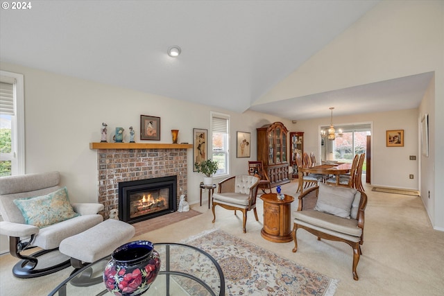 living room featuring a chandelier, light carpet, high vaulted ceiling, and a brick fireplace