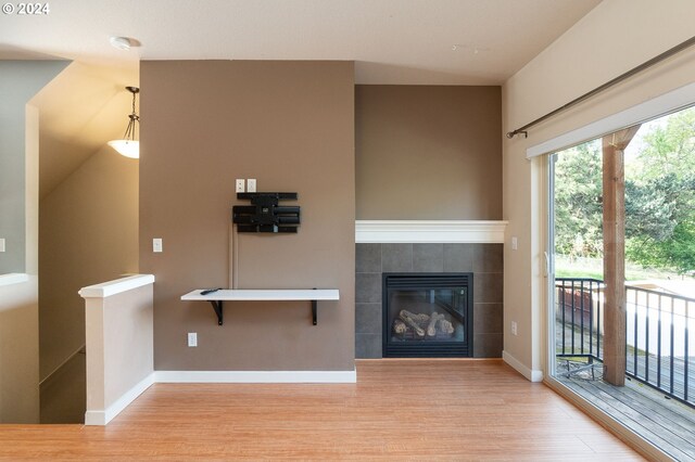 unfurnished living room featuring a tile fireplace and light hardwood / wood-style floors