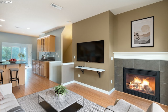 living room featuring light hardwood / wood-style flooring and a tile fireplace