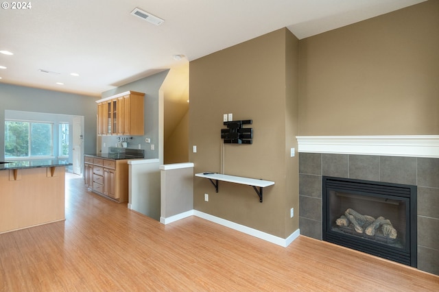 kitchen featuring a fireplace, light hardwood / wood-style floors, and a breakfast bar