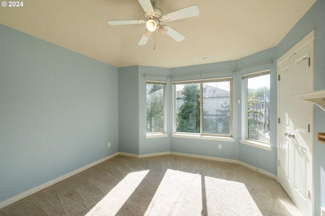 unfurnished room with a healthy amount of sunlight, light colored carpet, and ceiling fan