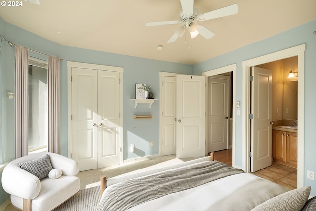 bedroom with a closet, connected bathroom, sink, light colored carpet, and ceiling fan