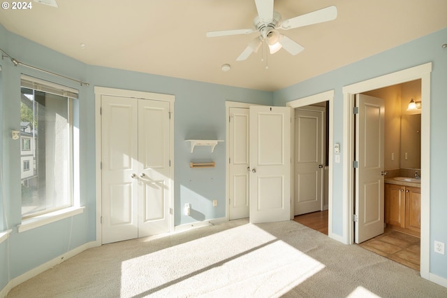 unfurnished bedroom featuring ensuite bathroom, ceiling fan, light carpet, a closet, and sink