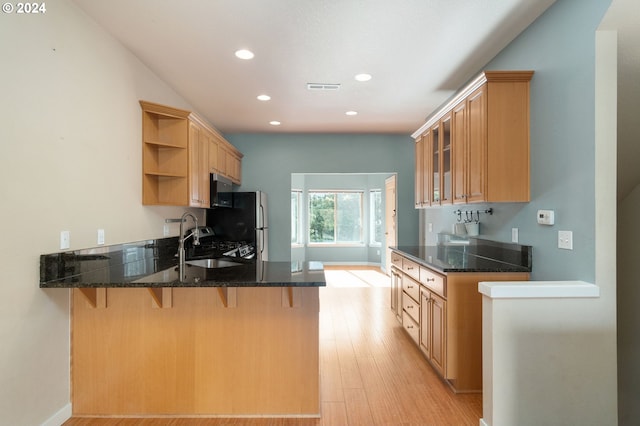 kitchen featuring sink, light hardwood / wood-style floors, kitchen peninsula, and dark stone counters