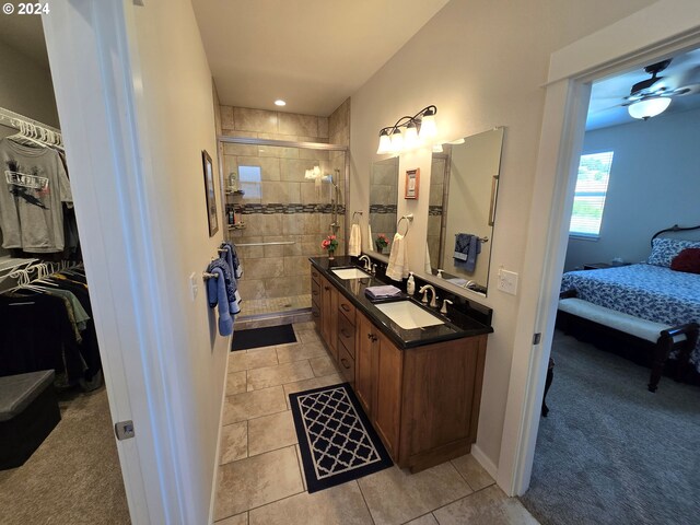 bathroom with ceiling fan, a shower with door, vanity, and tile patterned flooring