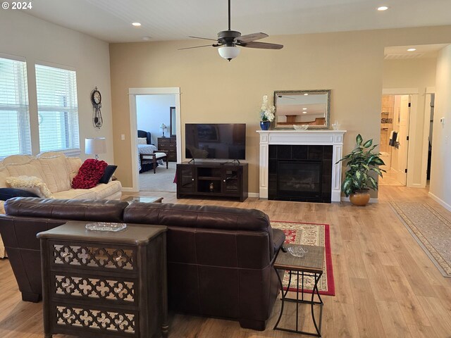 living room with ceiling fan, a fireplace, and light wood-type flooring