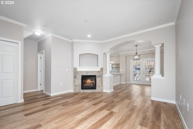 unfurnished living room with french doors, ornate columns, ornamental molding, light hardwood / wood-style flooring, and a tiled fireplace