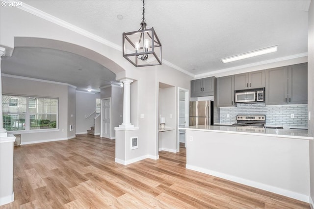 kitchen featuring crown molding, light hardwood / wood-style floors, decorative light fixtures, and appliances with stainless steel finishes