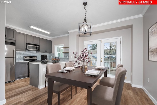 dining space featuring light hardwood / wood-style flooring, a chandelier, french doors, and ornamental molding