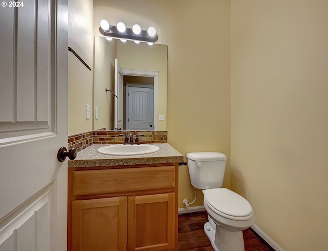 bathroom featuring vanity, toilet, wood-type flooring, and tasteful backsplash