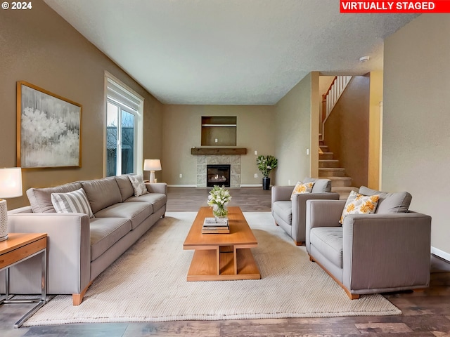 living room with a tile fireplace, a textured ceiling, and hardwood / wood-style flooring