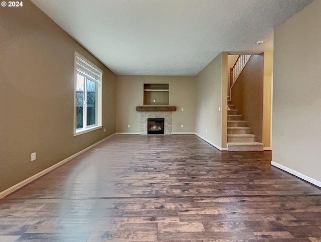 unfurnished living room featuring a textured ceiling, a fireplace, and dark wood-type flooring