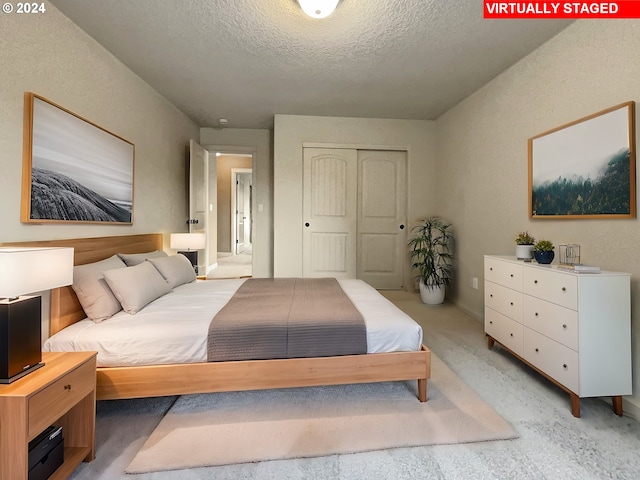 bedroom with a textured ceiling, light colored carpet, and a closet