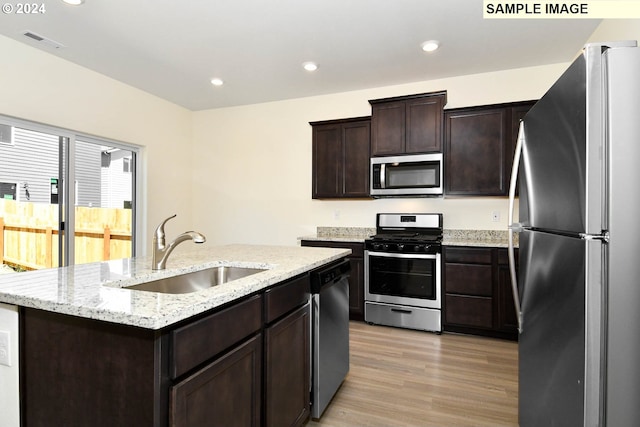 kitchen with sink, dark brown cabinets, a center island with sink, light hardwood / wood-style flooring, and stainless steel appliances