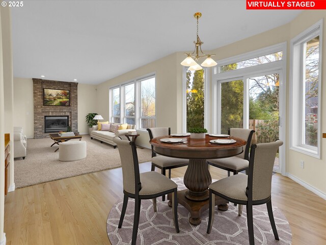 dining room with a fireplace, baseboards, and light wood-style floors