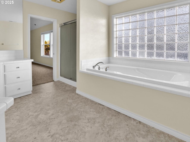 bathroom with a bath, baseboards, and a stall shower