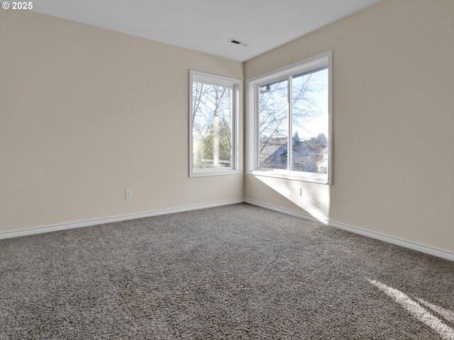 carpeted spare room featuring visible vents and baseboards