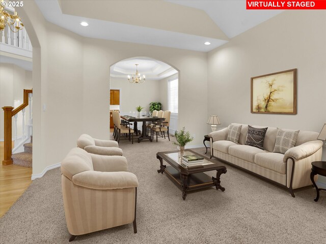 living area featuring arched walkways, stairway, recessed lighting, and a raised ceiling