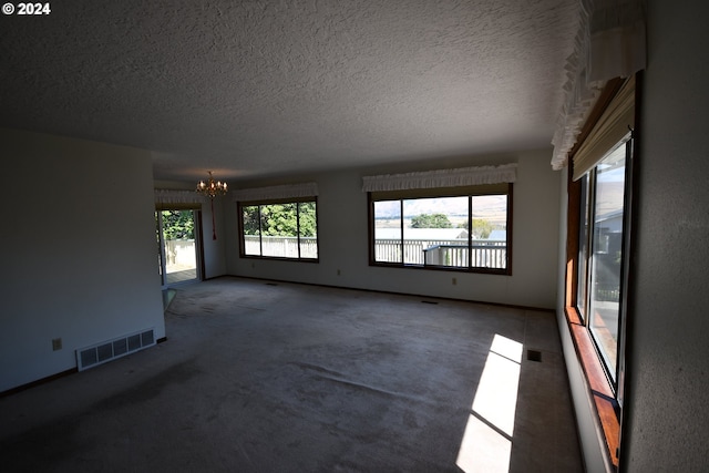 unfurnished living room featuring an inviting chandelier, a textured ceiling, and carpet