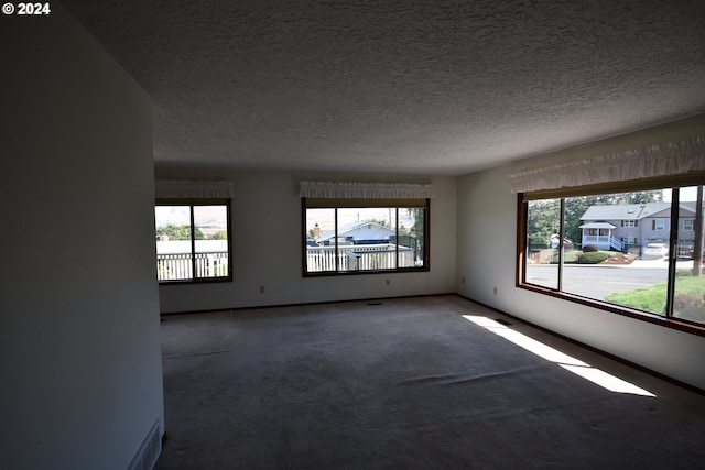 carpeted empty room with a textured ceiling