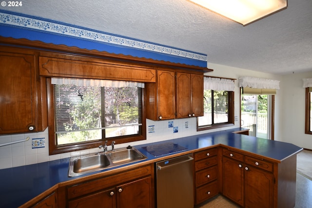 kitchen featuring sink, tasteful backsplash, a textured ceiling, stainless steel dishwasher, and kitchen peninsula