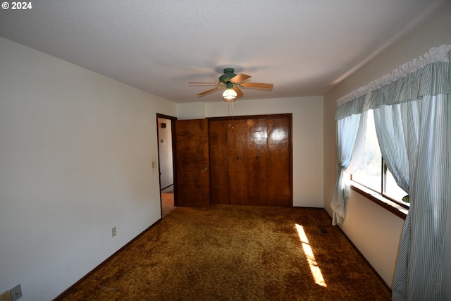 unfurnished bedroom featuring dark carpet, a closet, and ceiling fan