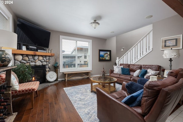 living room with a stone fireplace, stairway, hardwood / wood-style flooring, and baseboards