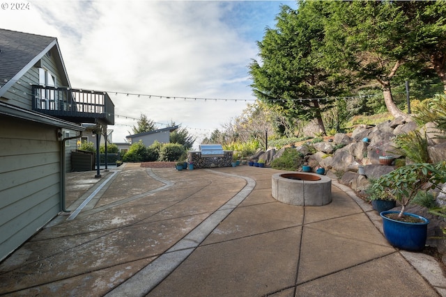 view of patio / terrace with an outdoor fire pit and a balcony