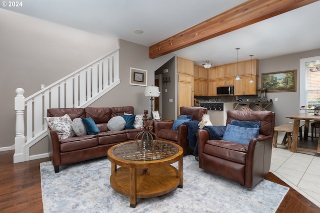 living area with beam ceiling, stairway, baseboards, and wood finished floors