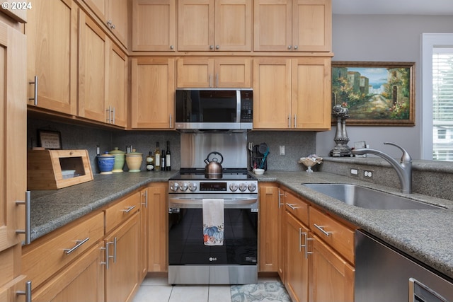 kitchen with light tile patterned floors, stainless steel appliances, a sink, and decorative backsplash