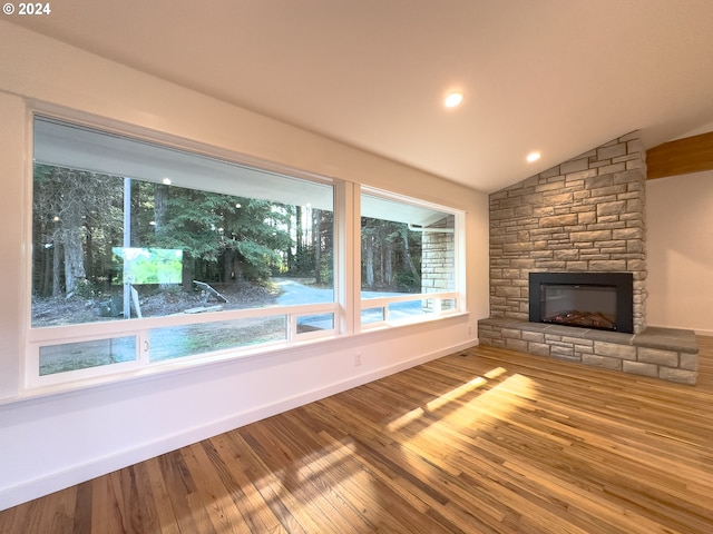 unfurnished living room with a fireplace, wood-type flooring, and lofted ceiling