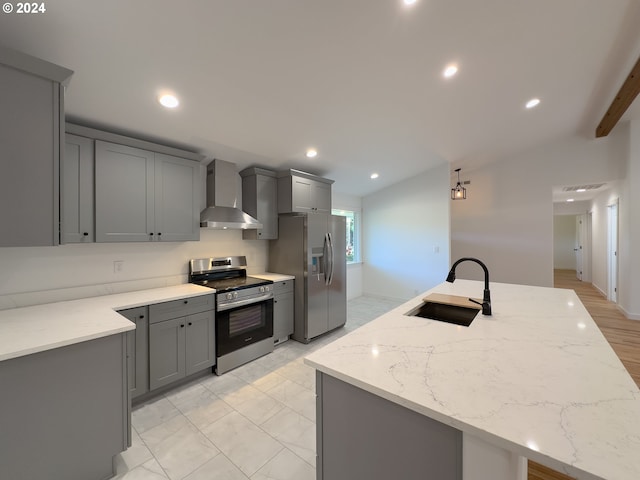 kitchen with appliances with stainless steel finishes, sink, light stone counters, and wall chimney range hood