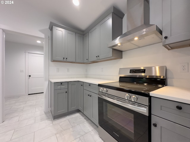 kitchen with wall chimney range hood, electric range, gray cabinets, and light tile patterned floors