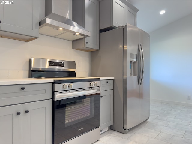 kitchen with gray cabinets, appliances with stainless steel finishes, light tile patterned flooring, and wall chimney exhaust hood