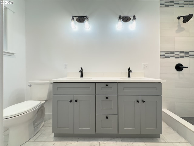 bathroom featuring tile patterned flooring, toilet, a tile shower, and vanity